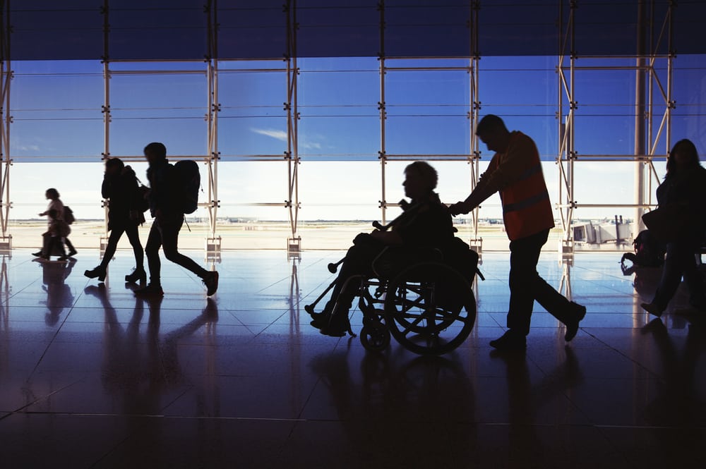 wheelchair user getting pushed by attendant at the airport